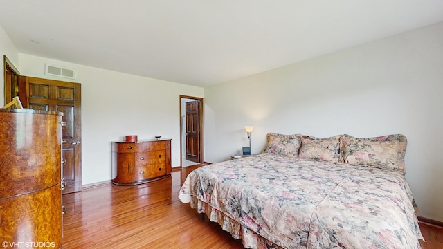 bedroom with baseboards, wood finished floors, and visible vents