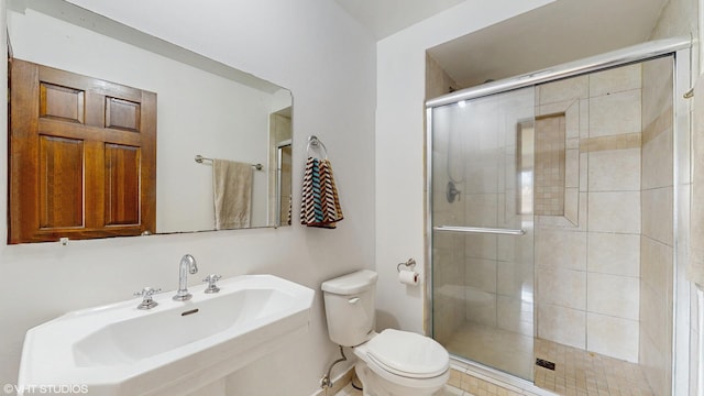 bathroom with a sink, toilet, and a shower stall