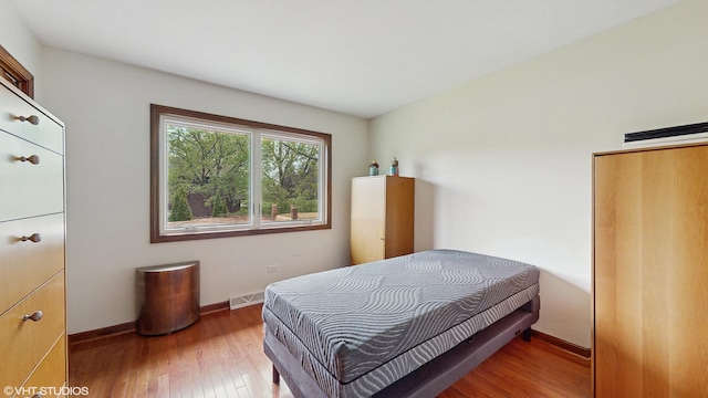 bedroom featuring baseboards, wood finished floors, and visible vents