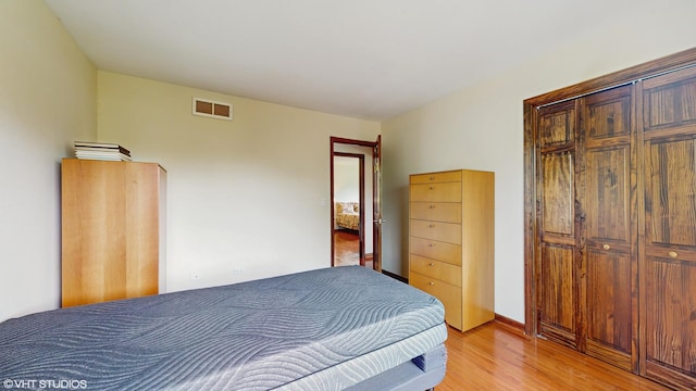 bedroom with baseboards, light wood-type flooring, and visible vents