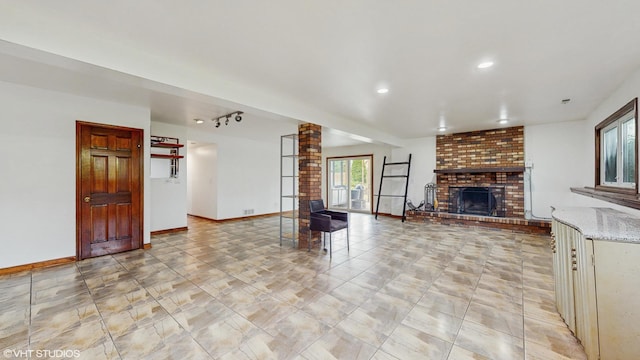 unfurnished living room featuring a brick fireplace, recessed lighting, baseboards, and decorative columns
