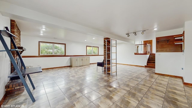 tiled spare room featuring stairway and baseboards