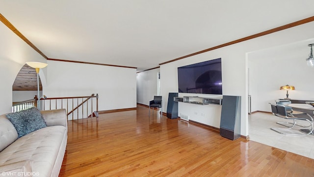 living area with crown molding, baseboards, light wood-style floors, and visible vents