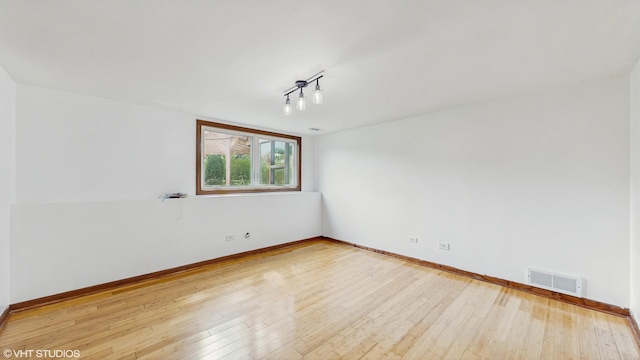 spare room featuring visible vents, baseboards, and hardwood / wood-style flooring