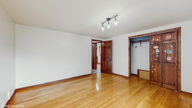unfurnished bedroom with baseboards, a closet, and light wood-type flooring