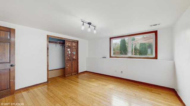 unfurnished bedroom with baseboards, visible vents, light wood finished floors, and a closet