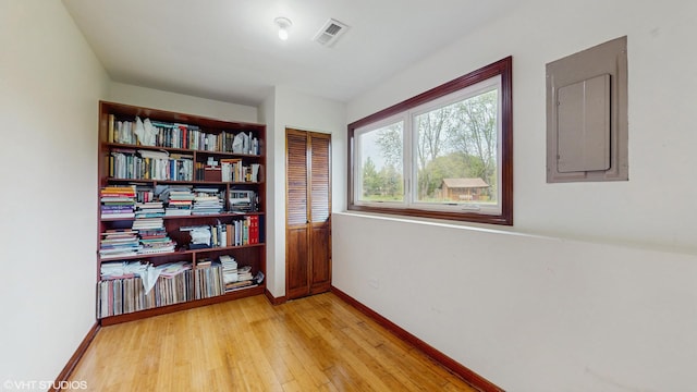 unfurnished room with baseboards, electric panel, light wood-style flooring, and visible vents