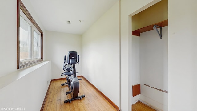 exercise area featuring visible vents, light wood finished floors, and baseboards
