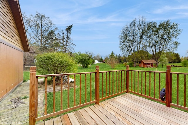 wooden deck featuring a lawn, an outdoor structure, and a shed