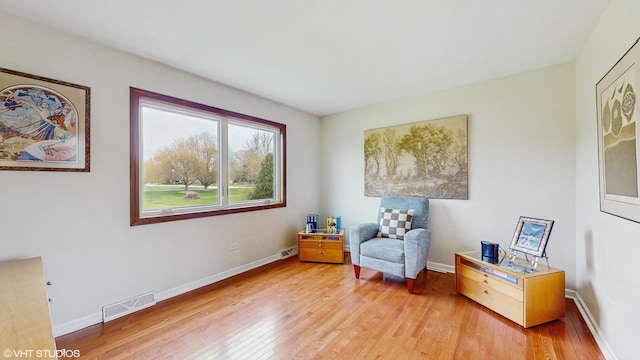 sitting room featuring baseboards, visible vents, and light wood-type flooring
