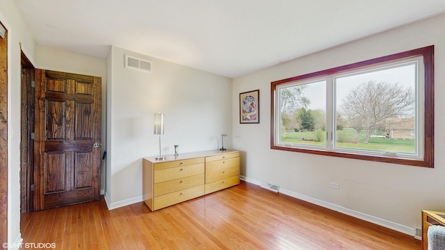 bedroom with visible vents, light wood finished floors, and baseboards