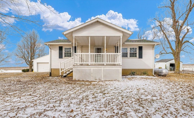 view of front of home featuring covered porch, roof with shingles, and a detached garage