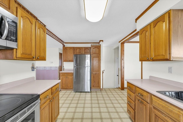 kitchen featuring light countertops, stainless steel appliances, brown cabinetry, and light floors