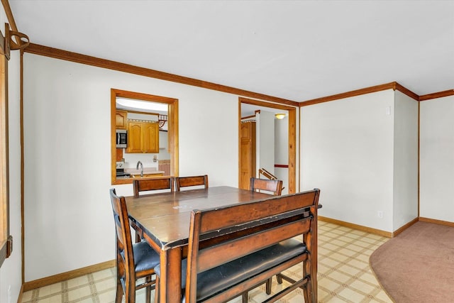 dining room with baseboards, ornamental molding, and light floors