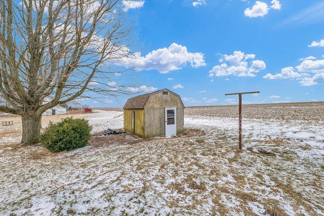 snow covered structure with an outbuilding and a storage shed
