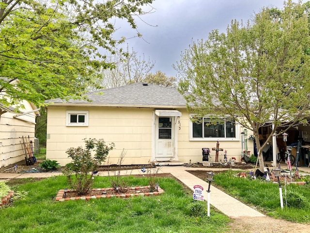 view of front of home with a front yard and roof with shingles