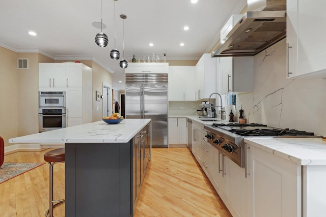 kitchen with stainless steel appliances, a sink, under cabinet range hood, crown molding, and a kitchen island