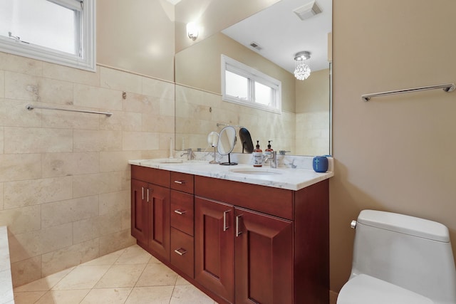 bathroom featuring toilet, tile walls, double vanity, and tile patterned flooring