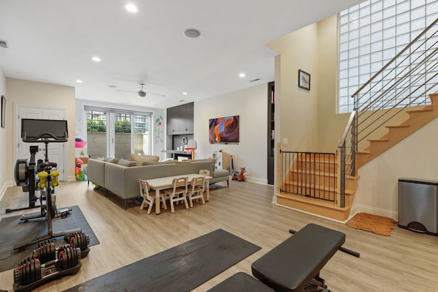 living room with light wood-type flooring, ceiling fan, baseboards, stairs, and recessed lighting