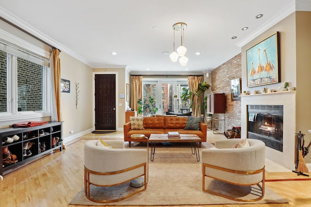 living room with ornamental molding, light wood-style flooring, a glass covered fireplace, baseboards, and recessed lighting