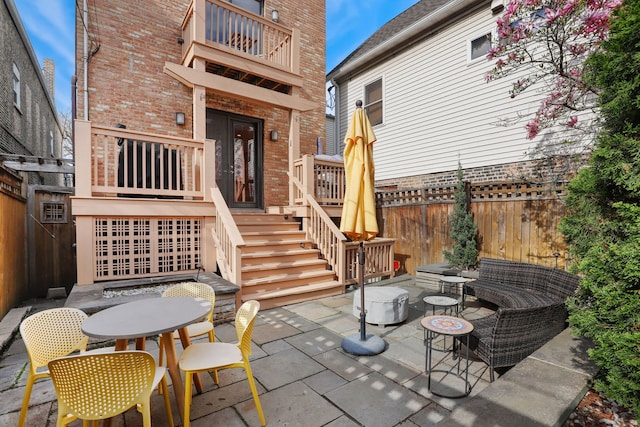 view of patio / terrace featuring stairway, a balcony, a fenced backyard, an outdoor living space, and french doors