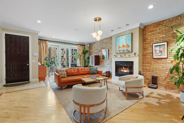 living area featuring wood finished floors, brick wall, ornamental molding, a glass covered fireplace, and recessed lighting