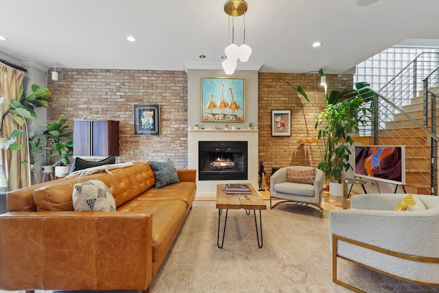 living area with a warm lit fireplace, brick wall, ornamental molding, and recessed lighting
