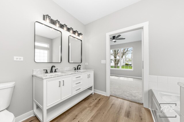 bathroom with toilet, ceiling fan, a sink, and wood finished floors