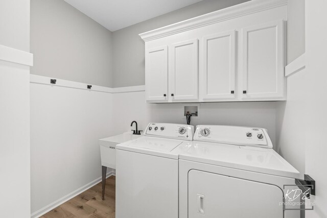 clothes washing area featuring light wood-style floors, baseboards, cabinet space, and washing machine and clothes dryer