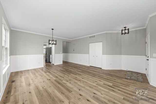 unfurnished dining area with visible vents, wainscoting, light wood-type flooring, and a chandelier