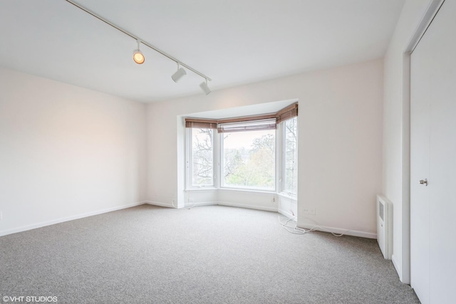 unfurnished room with baseboards, carpet flooring, and rail lighting