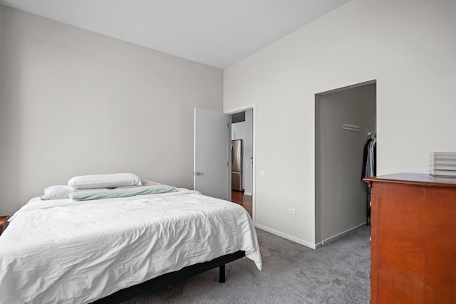 carpeted bedroom featuring baseboards and freestanding refrigerator