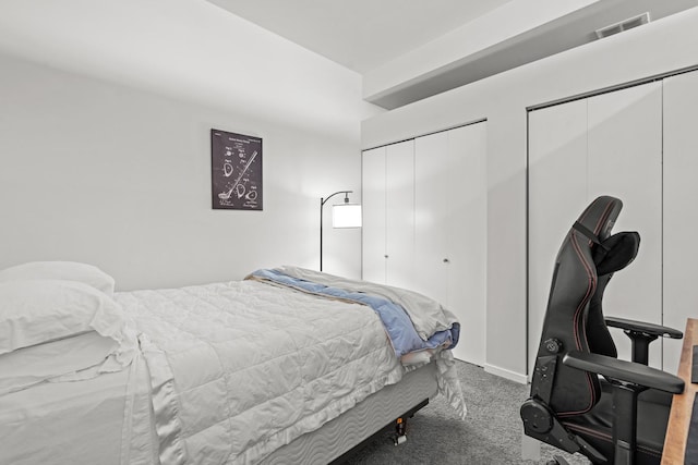 bedroom featuring visible vents, multiple closets, and carpet