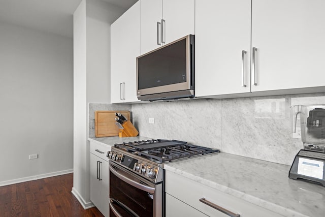 kitchen featuring appliances with stainless steel finishes, white cabinets, dark wood-style flooring, and light stone counters