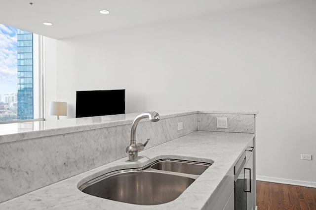 kitchen featuring light stone counters, a sink, dark wood finished floors, recessed lighting, and baseboards