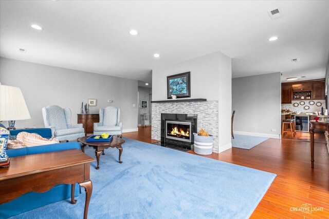 living area featuring recessed lighting, baseboards, a fireplace with flush hearth, wood finished floors, and visible vents