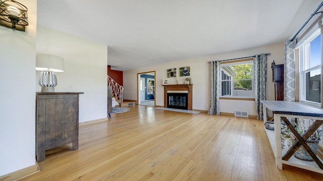 1008 Mary Ave, Dixon, IL 61021 - unfurnished living room with light wood-type flooring, stairway, a fireplace with flush hearth, and baseboards