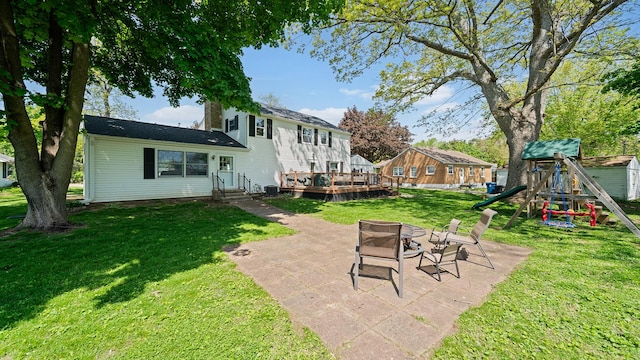 1008 Mary Ave, Dixon, IL 61021 - view of green lawn featuring a playground, a fire pit, a patio area, and a wooden deck