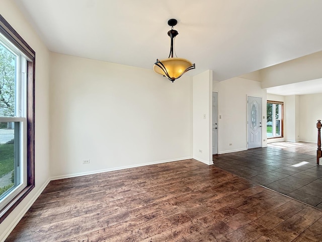 spare room with a healthy amount of sunlight, baseboards, and dark wood finished floors