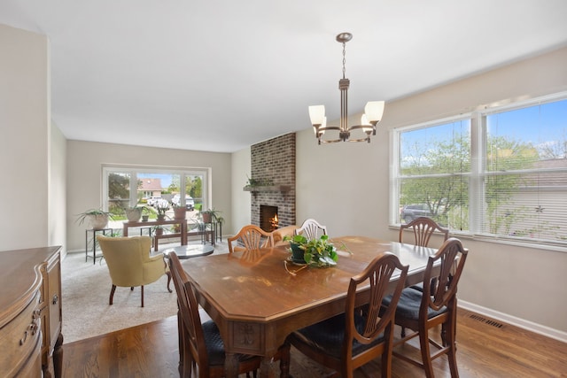 759 Dunmore Ln, Bartlett, IL 60103 - dining room featuring baseboards, visible vents, a brick fireplace, a chandelier, and dark wood-type flooring