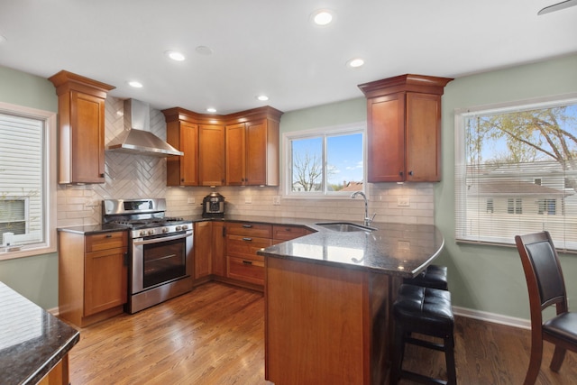 759 Dunmore Ln, Bartlett, IL 60103 - kitchen with a peninsula, stainless steel gas range, a kitchen bar, a sink, and wall chimney exhaust hood