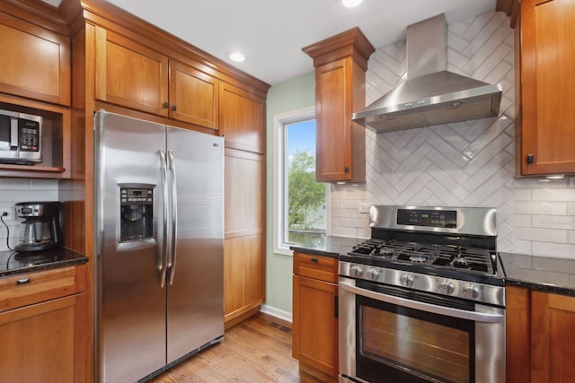 759 Dunmore Ln, Bartlett, IL 60103 - kitchen featuring dark stone counters, wall chimney exhaust hood, stainless steel appliances, and brown cabinets