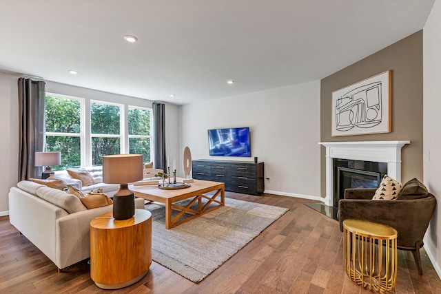 living area with baseboards, a fireplace with flush hearth, recessed lighting, and hardwood / wood-style floors
