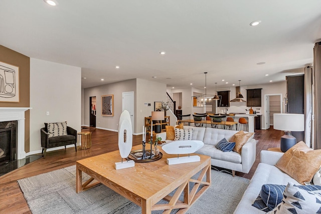 living room with recessed lighting, a high end fireplace, dark wood-style floors, and stairway