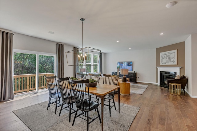 dining room with recessed lighting, a glass covered fireplace, and hardwood / wood-style flooring