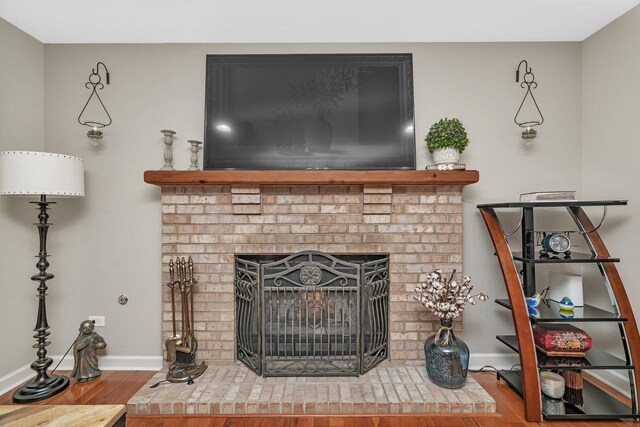 room details with baseboards, wood finished floors, and a fireplace