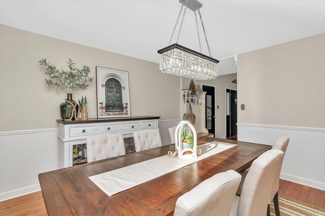 dining area featuring baseboards, an inviting chandelier, and light wood-style floors