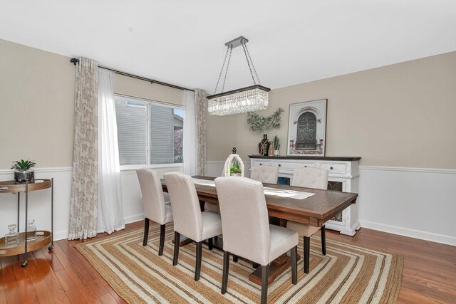 dining space with baseboards, a notable chandelier, and hardwood / wood-style floors