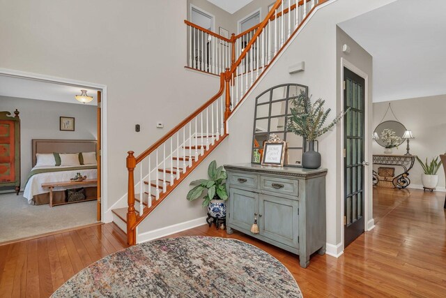 stairs featuring baseboards, wood-type flooring, and a towering ceiling