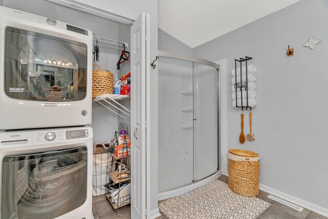 full bath featuring vaulted ceiling, stacked washer and clothes dryer, a stall shower, and visible vents